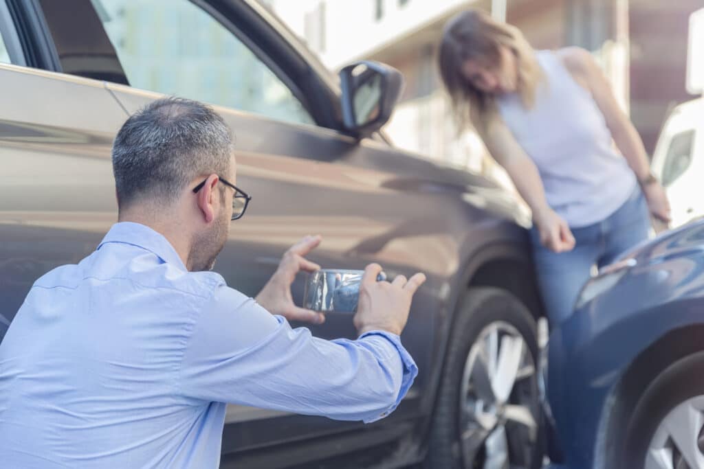A man clicking photos of a damaged vehicle in a car accident
